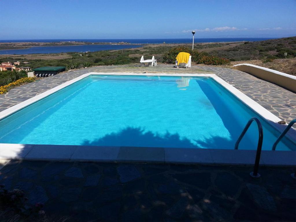 a large blue swimming pool with a view of the ocean at Villa Aura in Stintino