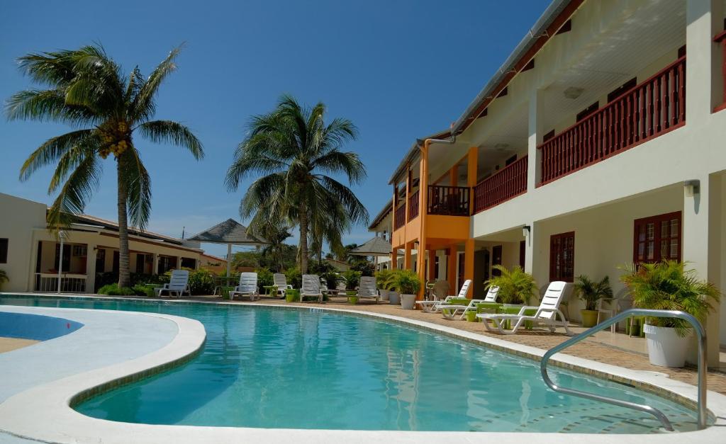 a swimming pool in front of a hotel with palm trees at Aruba Quality Apartments & Suites in Palm-Eagle Beach