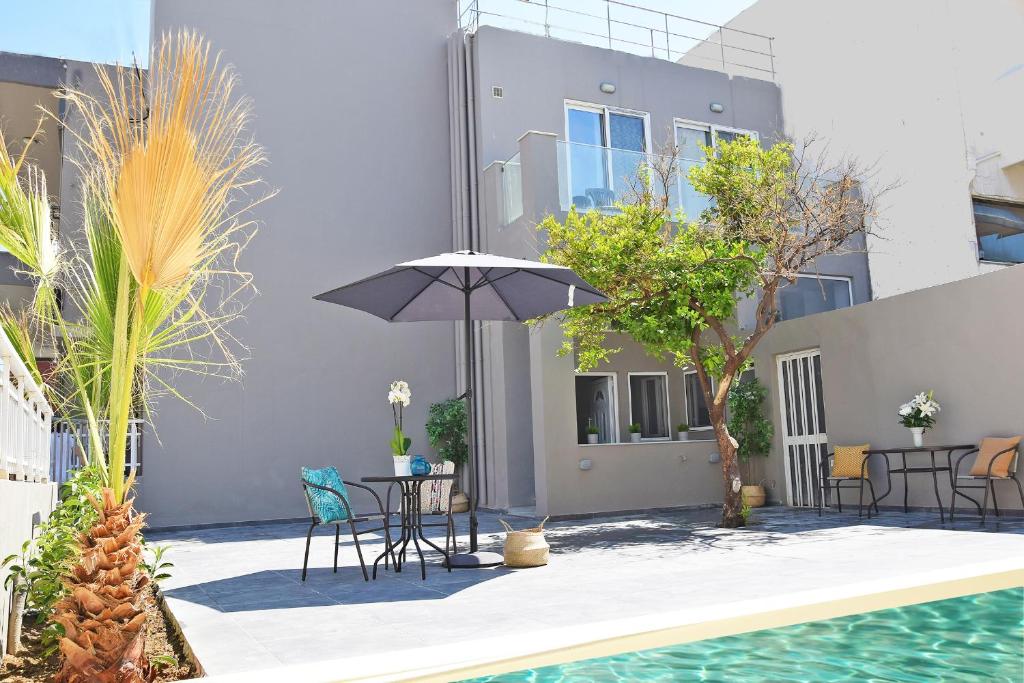 - une terrasse avec une table et un parasol à côté de la piscine dans l'établissement CreteSuites - Urban Villa with Pool - 500m to the Beach, à Réthymnon
