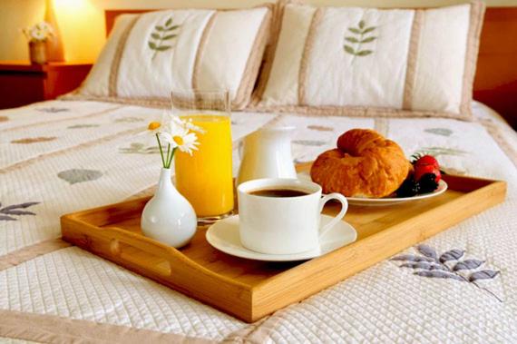 a tray of food and a cup of coffee on a bed at Allurapart Plaza in Kyiv