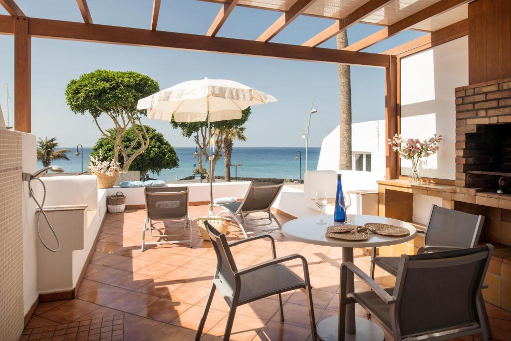 une terrasse avec une table et des chaises et l'océan dans l'établissement Kallao Apartment, à Puerto del Carmen
