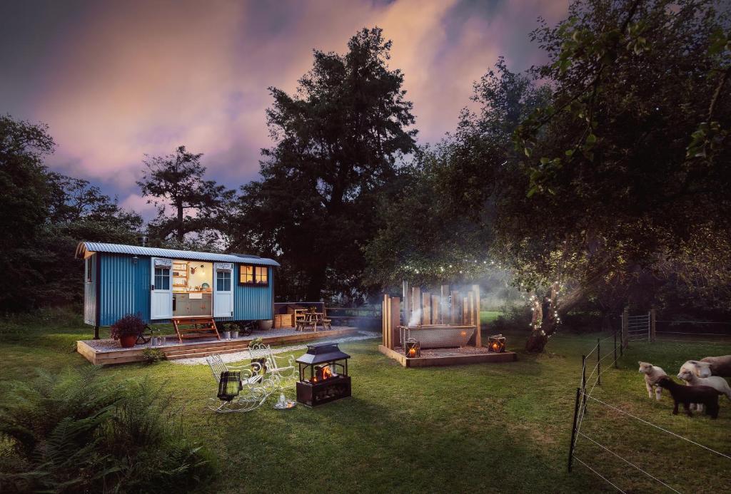 a blue tiny house in a yard with a grill at The Wriggly Tin at Tregoose Old Mill in Newquay