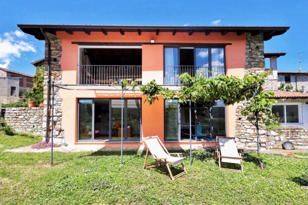 a house with two lawn chairs in front of it at Nido d’amore nei colori in Dernice