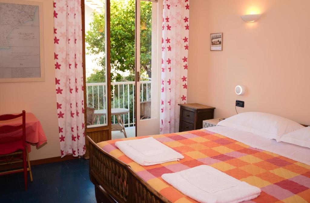 ライグエーリアにあるPoggio del soleのベッドルーム1室(ベッド1台付)、窓、バルコニーが備わります。