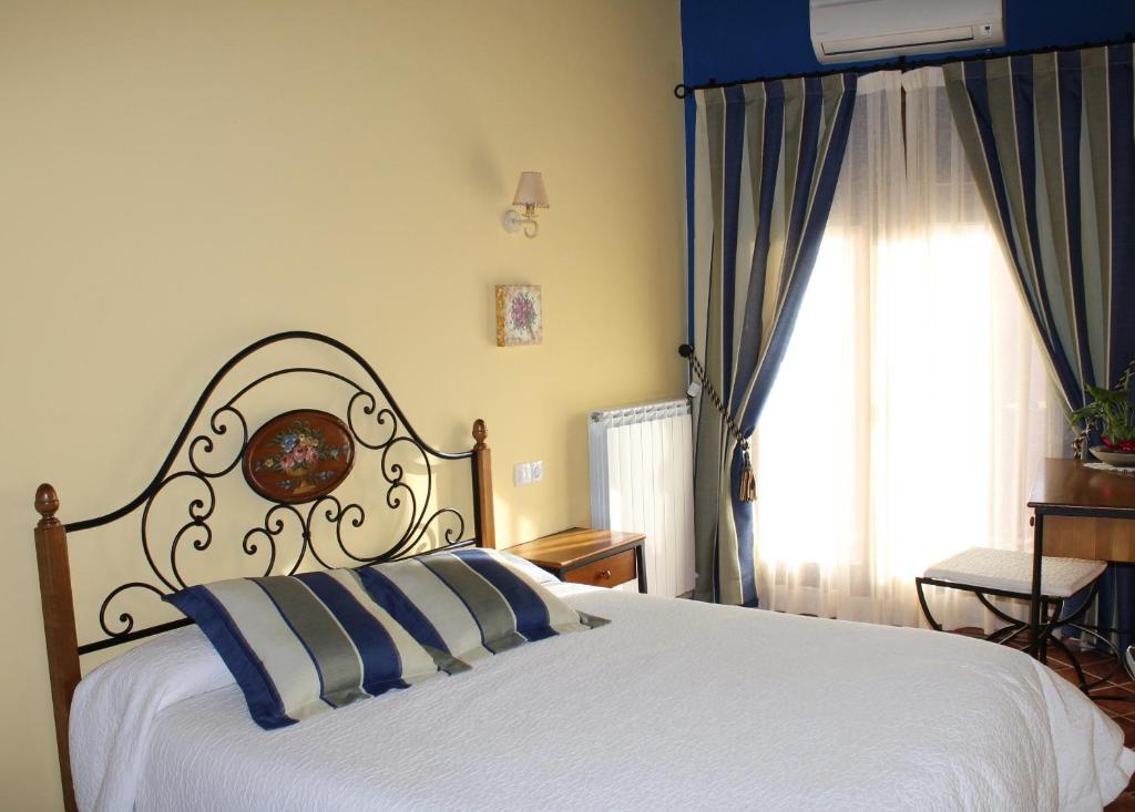 1 dormitorio con cama blanca y ventana en El Corral de Valero, en Valdealgorfa