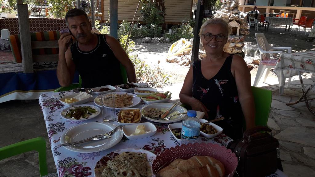 a man and a woman sitting at a table with food at Caunos bungalow in Muğla