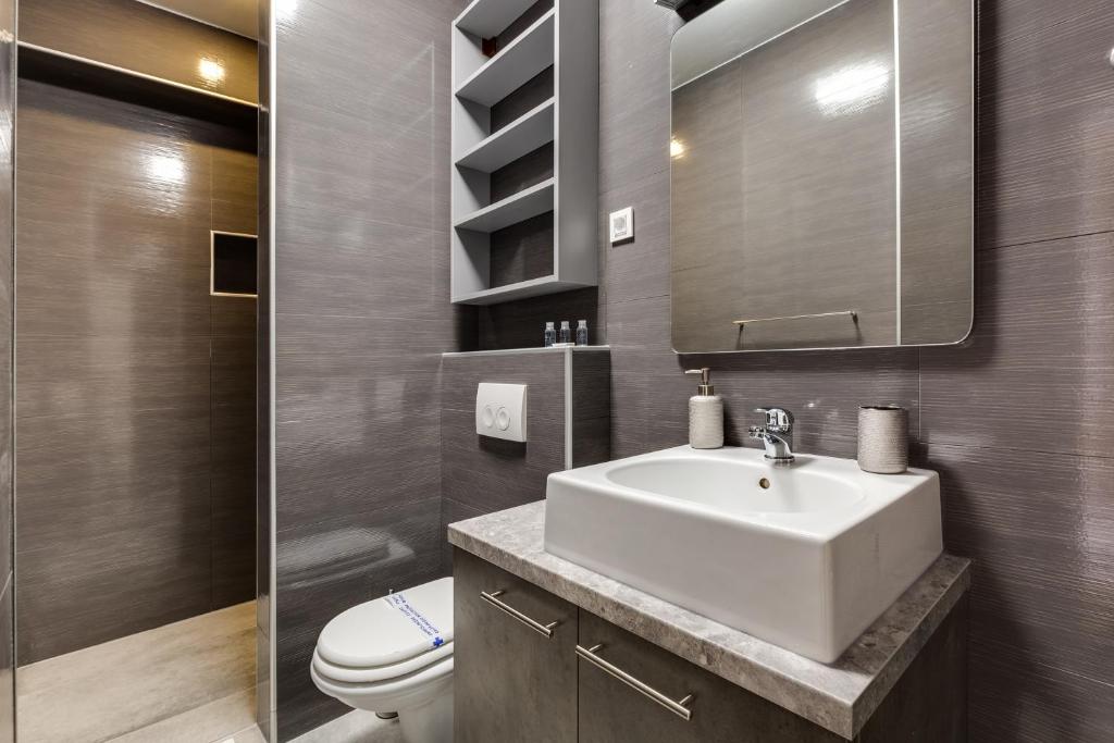 a bathroom with a sink and a toilet and a mirror at Hotel Sky in Zadar