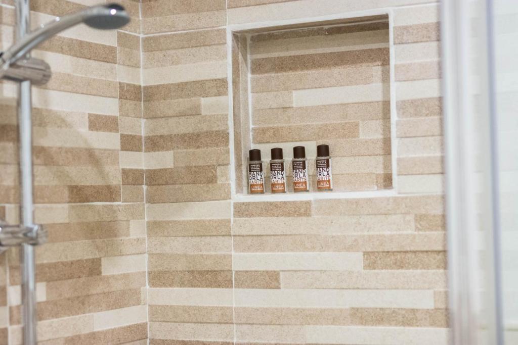 a bathroom with a shower with four bottles ofodorizers at La Casetta sul Mare in Isola delle Femmine