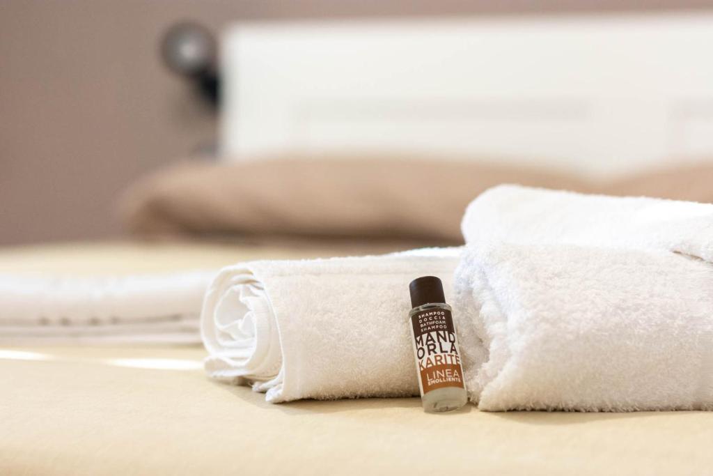 a bottle of soap sitting next to towels on a bed at La Casetta sul Mare in Isola delle Femmine