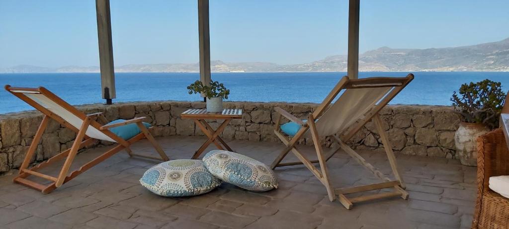 two chairs and a table with a view of the ocean at Le Grand Bleu in Sitia