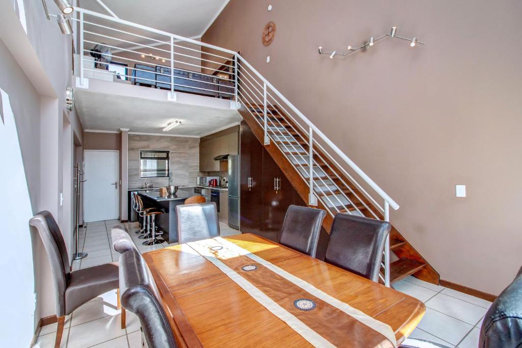 a dining room with a table and a staircase at Upmarket Ultra Modern Sandton Apartment in Johannesburg