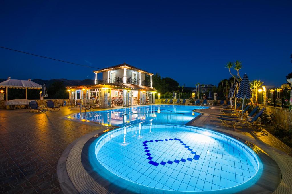 a swimming pool at night with a house in the background at MAKIS STUDIOS in Roda