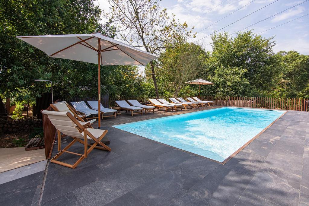 een zwembad met ligstoelen en een parasol bij Quinta do Pedregal Hotel & Spa in Vila Nova de Gaia