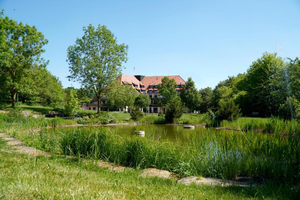 a pond in front of a building with a house at Flair Park Hotel Ilshofen in Ilshofen