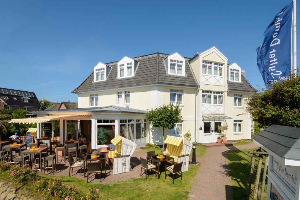 une grande maison blanche avec des tables et des chaises devant elle dans l'établissement Sylter Domizil, à Wenningstedt