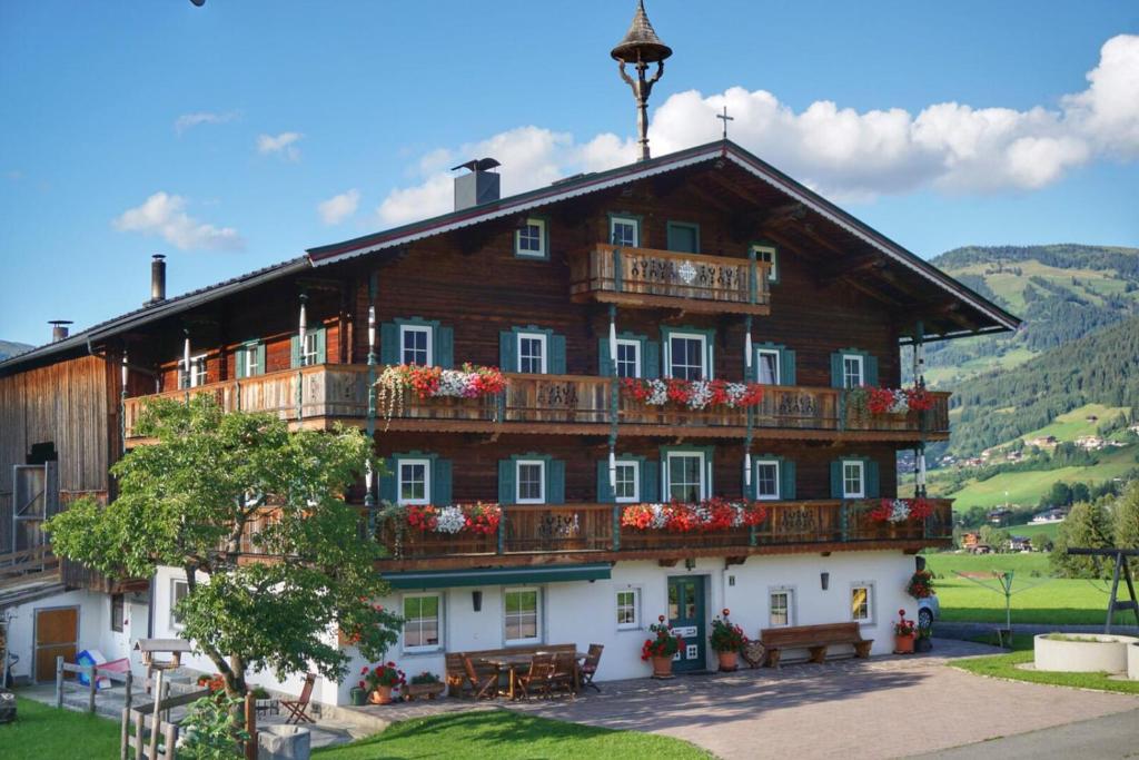 un grand bâtiment en bois avec des fleurs sur les balcons dans l'établissement Angererhof, à Jochberg