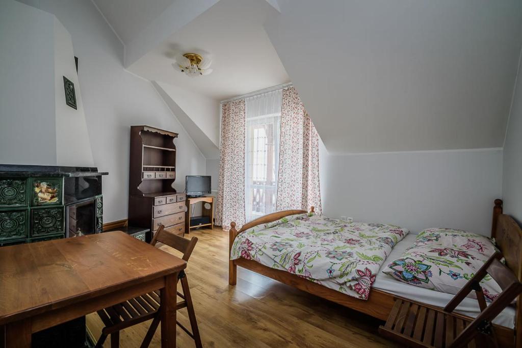 a bedroom with a bed and a table and a desk at Przytulne pokoje tuż obok szlaków pieszych i rowerowych, 800m do centrum in Szczawnica