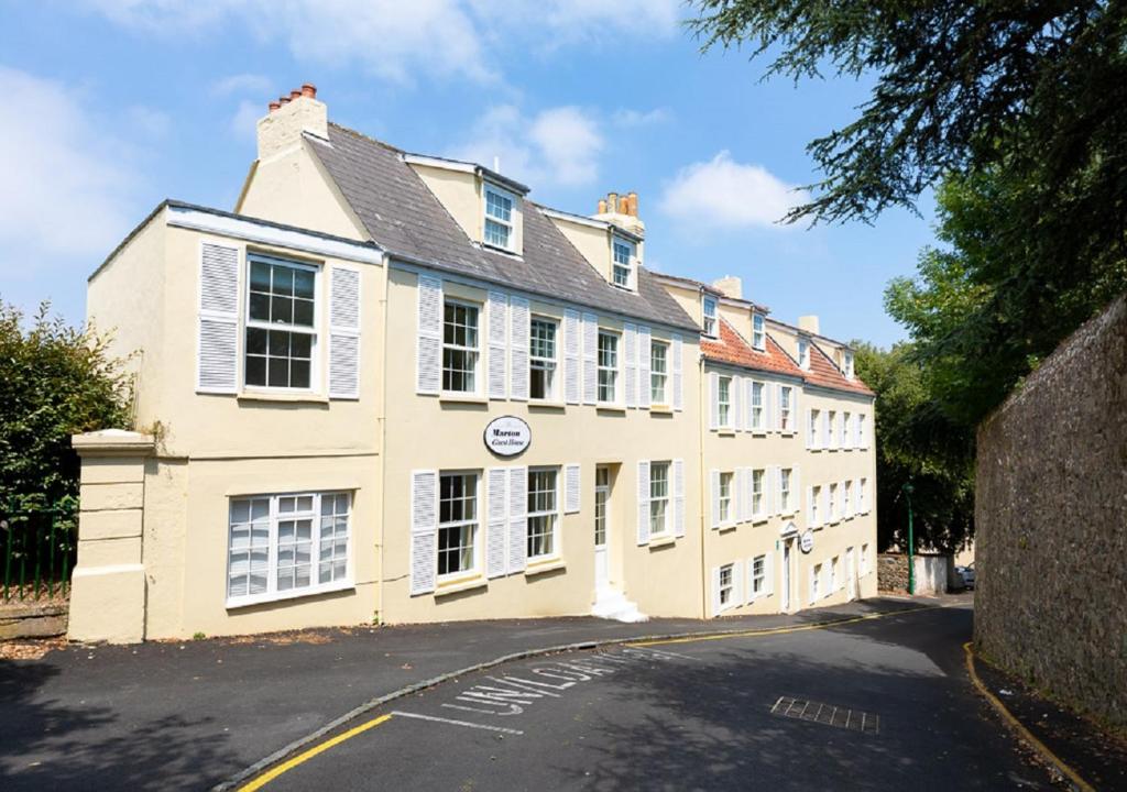 a large white building with white windows on a street at Marton Guest House in St Peter Port