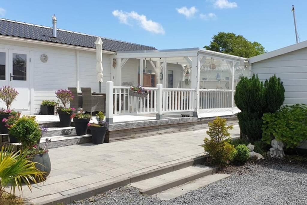 een wit huis met een patio met een tuinhuisje bij Prachtig Scandinavisch Chalet in Makkum