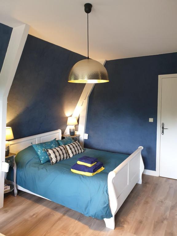Cama en habitación con pared azul en Chambre d’hôte Normande, en Freneuse-sur-Risle