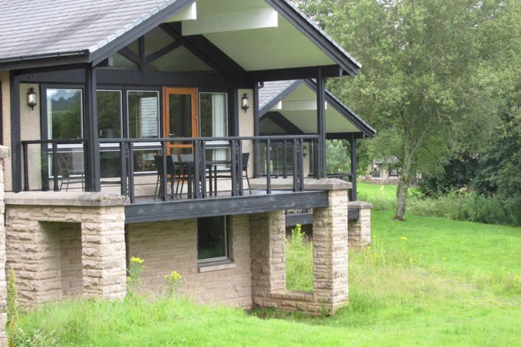 a house with a wrap around porch with a deck at Cameron House Lodge on Loch Lomond in Balloch