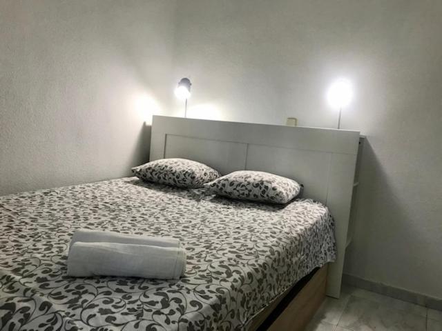 1 dormitorio con 1 cama con 2 almohadas y 2 luces en Rooms Arganzuela Centro, en Madrid