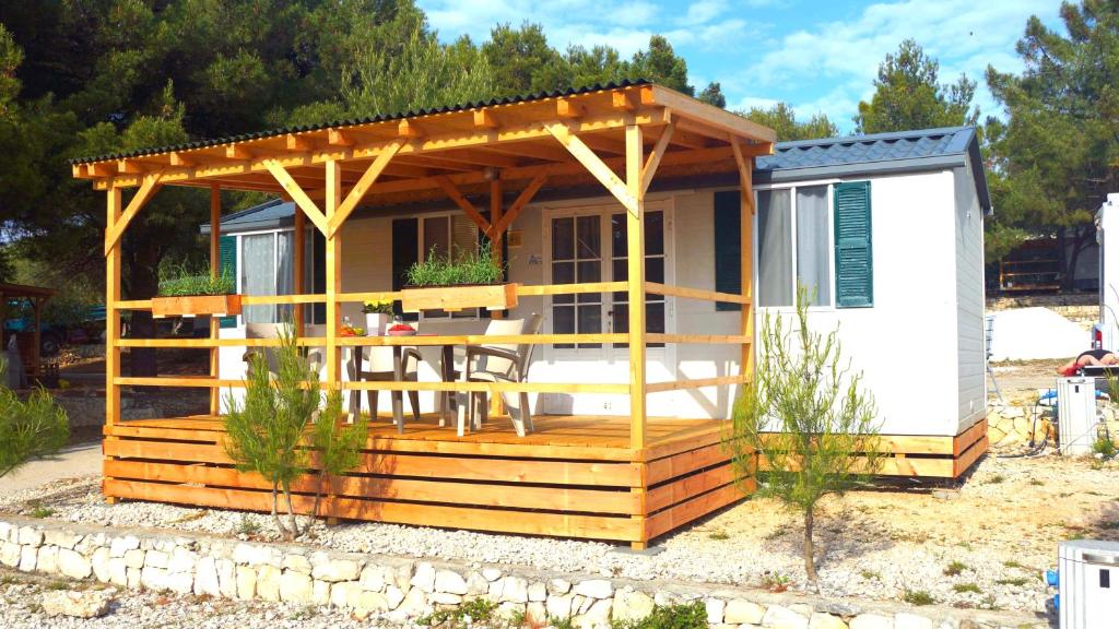 a tiny house with a deck with a pergola at Mobilehome Adams Glamping - Camp Adriatic in Primošten