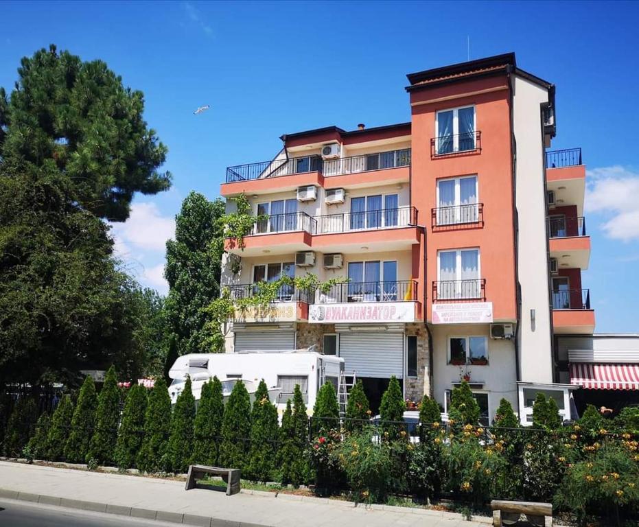 a tall apartment building with a fence and trees at Respekt Guest House in Sunny Beach