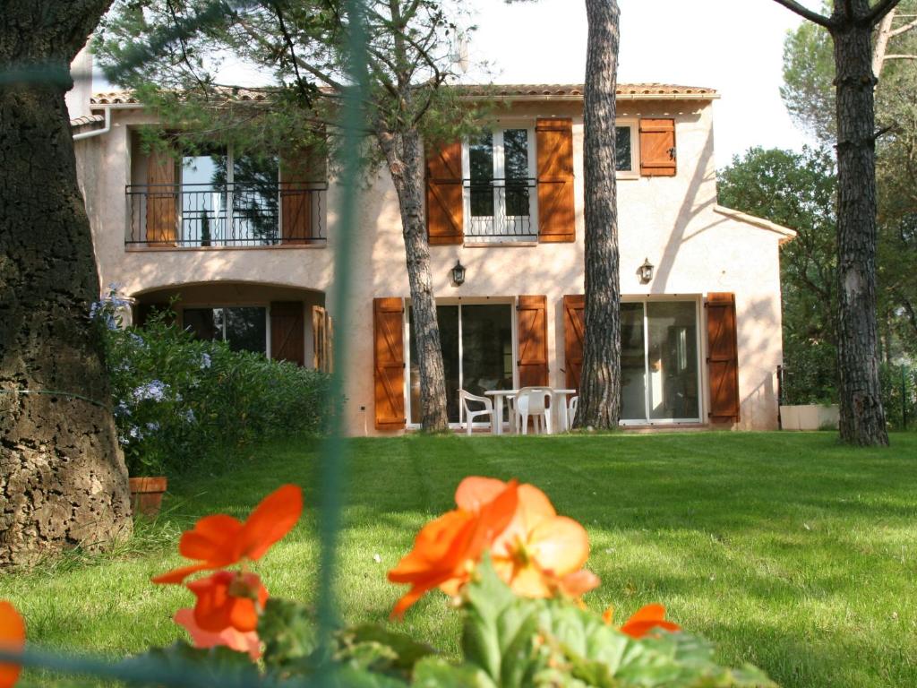 uma casa no fundo com flores de laranja no primeiro plano em Location Villa et Studios Roquebrune-sur-Argens em Roquebrune-sur-Argens