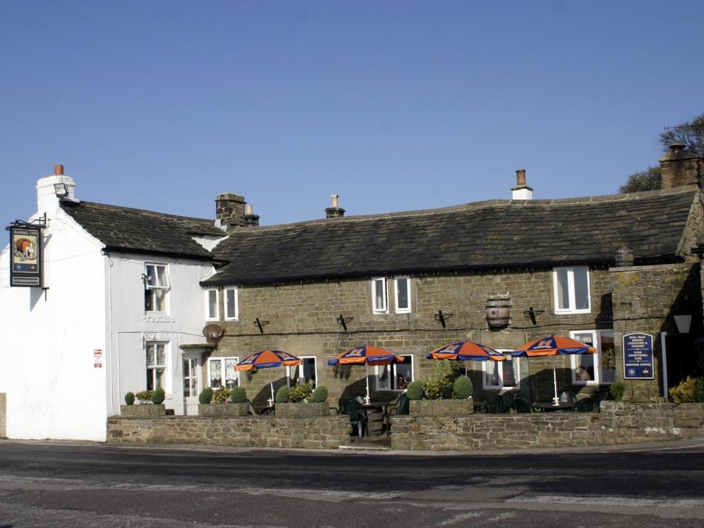 un vecchio edificio in pietra con ombrelloni di fronte di The Barrel Inn a Eyam