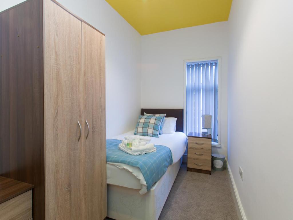 a small bedroom with a bed and a wooden cabinet at TownHouse @ West Avenue Crewe in Crewe