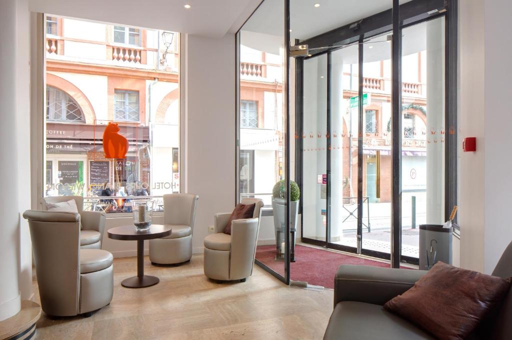 a lobby with chairs and a table and windows at Hotel Ours Blanc - Wilson in Toulouse