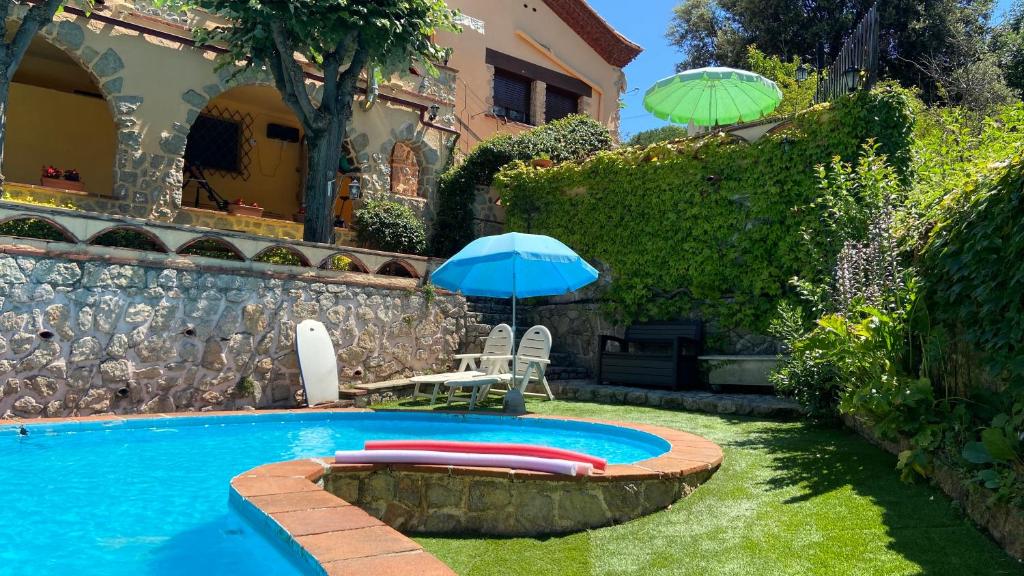 una piscina con ombrelloni e sedie e una casa di Apartment Vacarisses Torreblanca Estación, Piscina Privada a Vacarisas