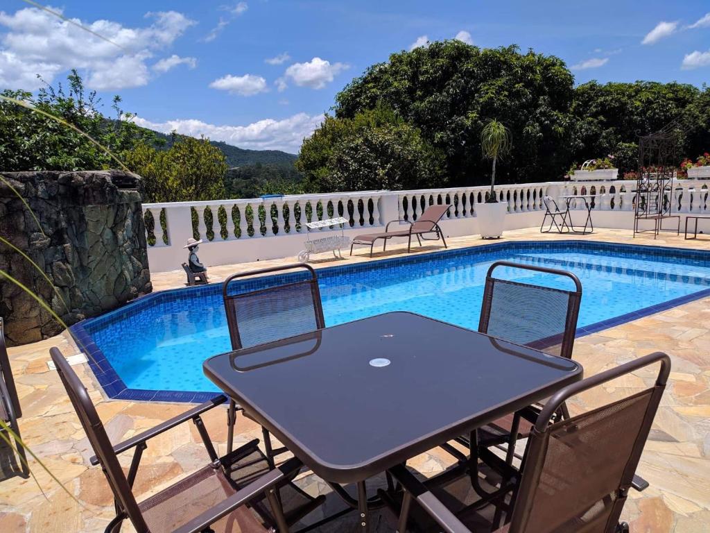 - une table et des chaises à côté de la piscine dans l'établissement Cantinho Romântico e Encantador, à Mairiporã