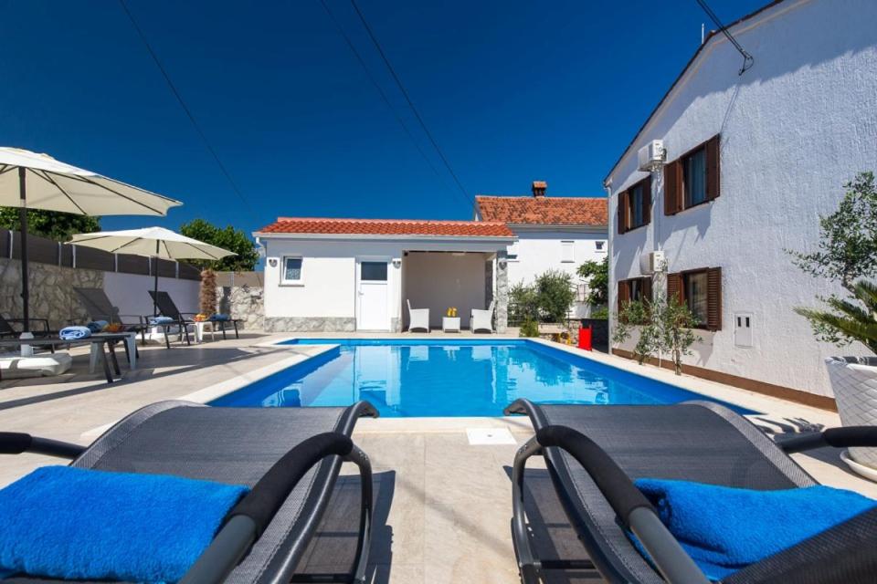 uma piscina com cadeiras ao lado de uma casa em ADRIA-Holiday House with a beautiful pool in Krk em Kornic
