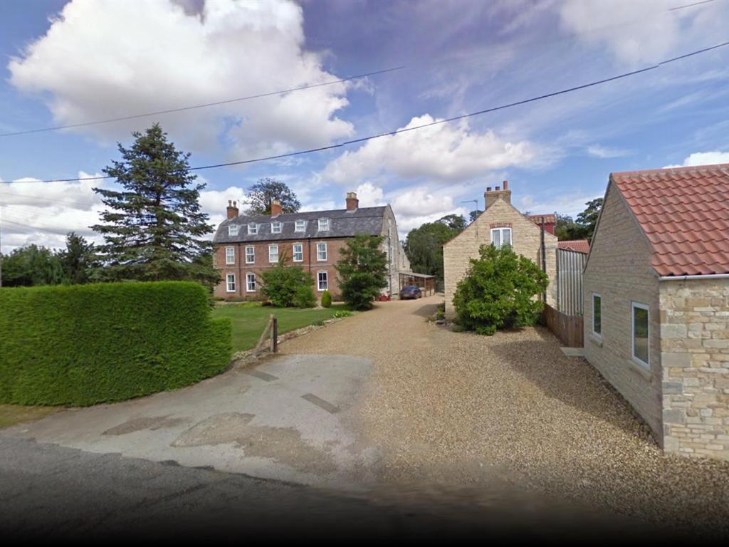 a driveway leading to a brick building with a house at BlackbullA1lodge in Grantham