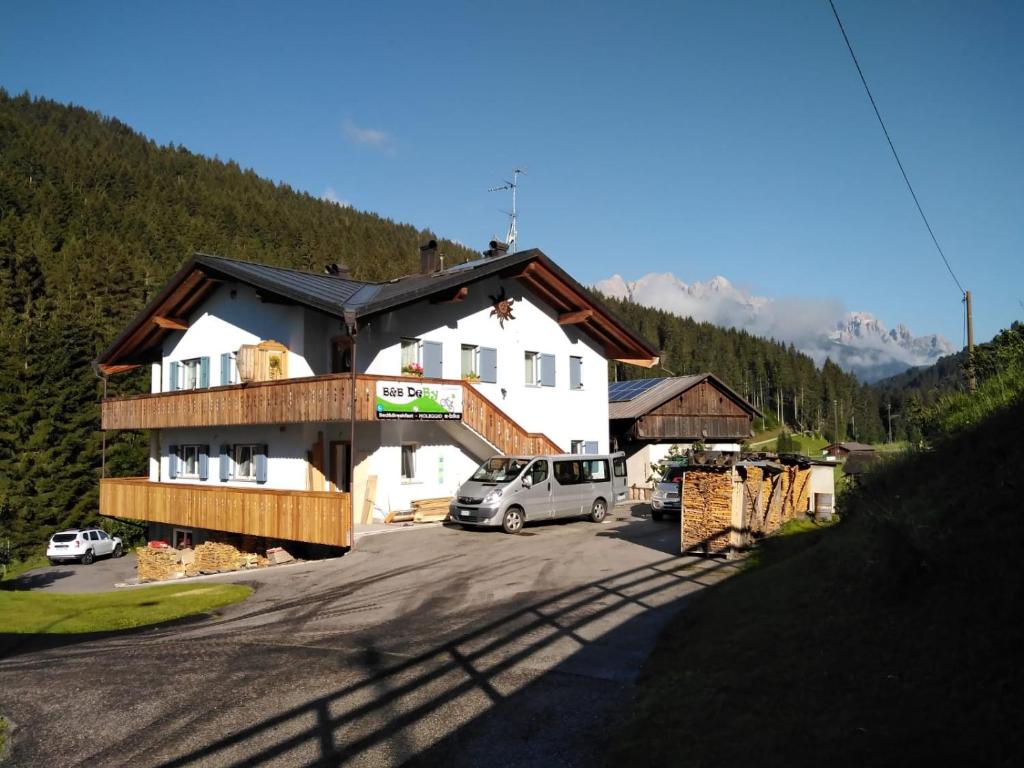 a house with a van parked in a parking lot at B&B DeBy & E-Bike Rental in San Niccolò Comèlico