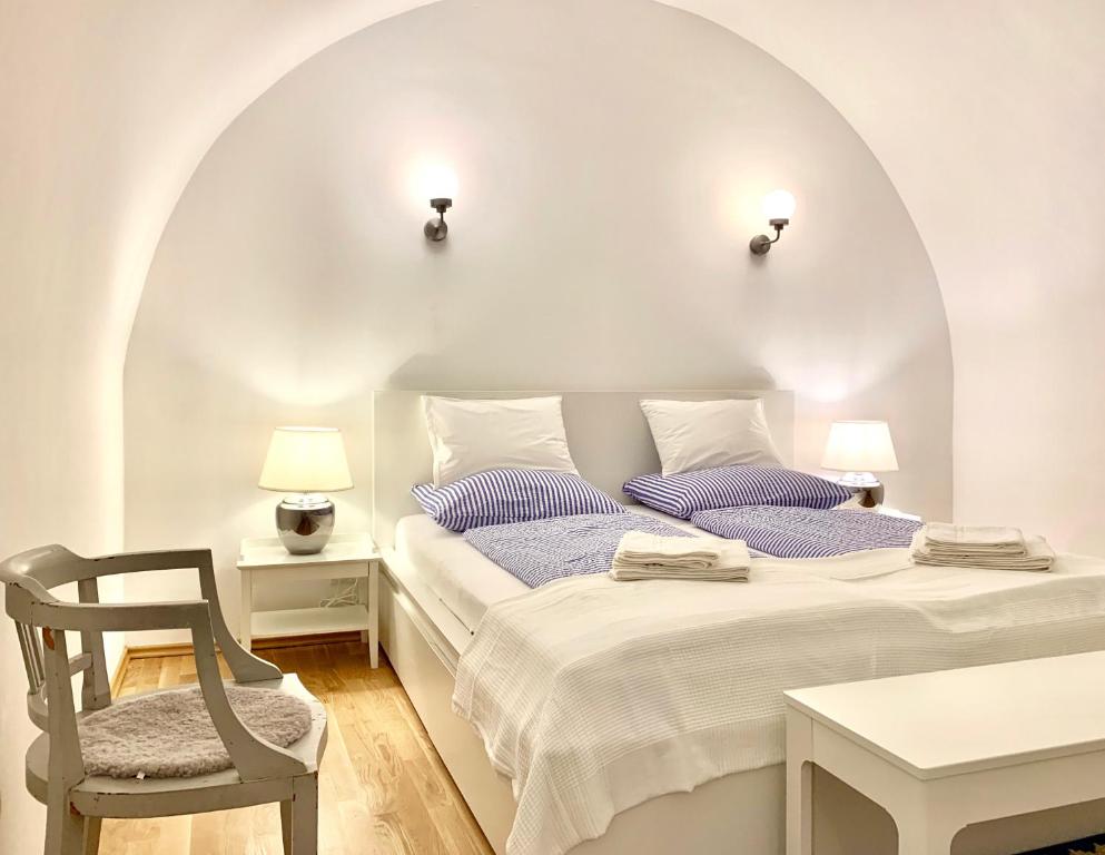 a white bedroom with a bed and a chair at Altstadt Apartments Melk mit Sauna in Melk