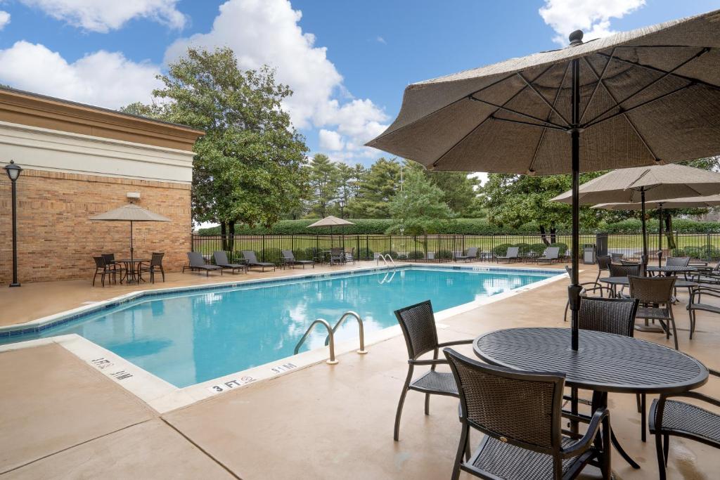 ハンツビルにあるHoliday Inn Huntsville - Research Park, an IHG Hotelのテーブルと椅子、パラソル付きのプールを提供しています。