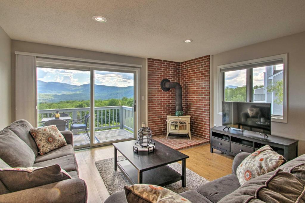 a living room with a couch and a television and a balcony at Family-Friendly Condo with Mtn Views, Community Pool in Intervale