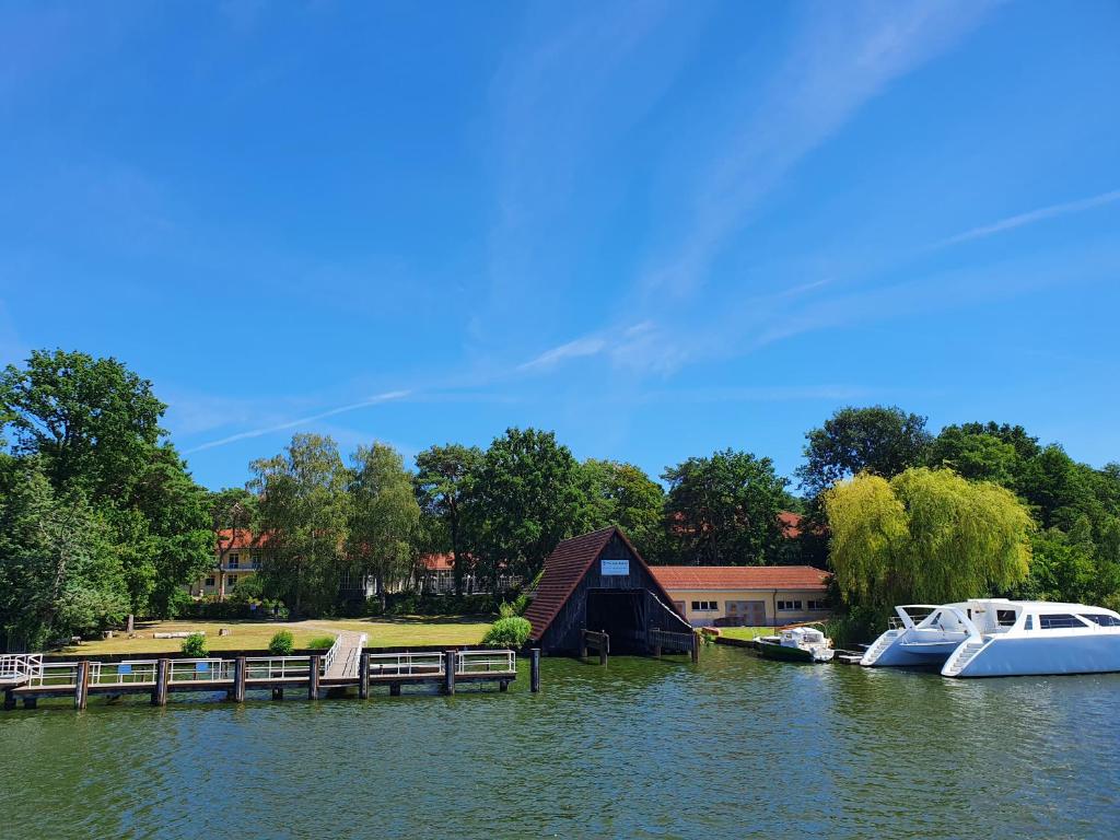 two boats are docked at a dock on a lake at Waldhotel am See Berlin-Schmöckwitz in Berlin