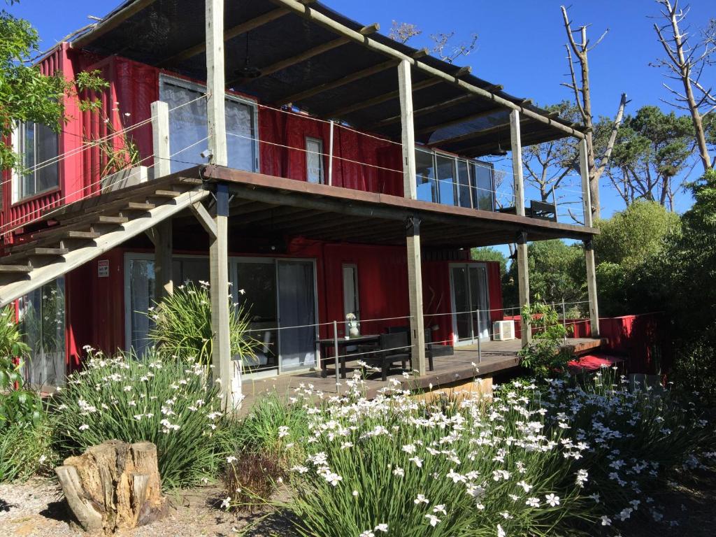 a red house with a balcony in a garden at Cdl in José Ignacio
