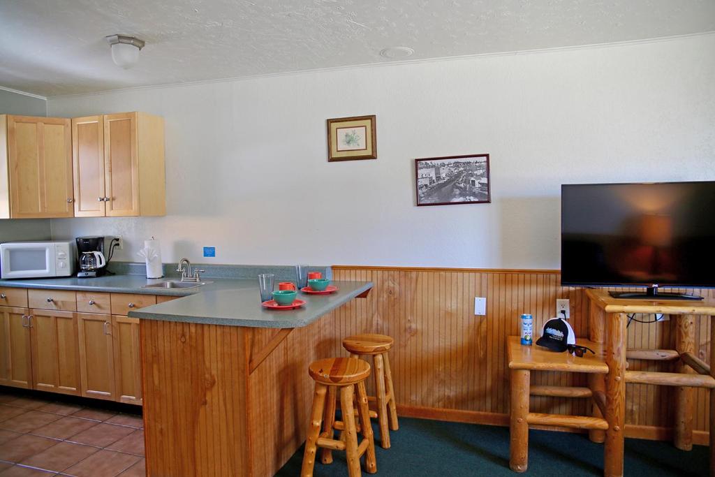 a kitchen with a bar with a tv and some stools at Healing Waters Resort and Spa in Pagosa Springs