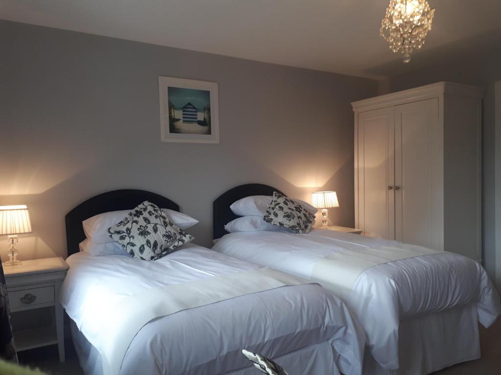 a bedroom with two beds and a chandelier at Berry House Bed & Breakfast in Littlehampton