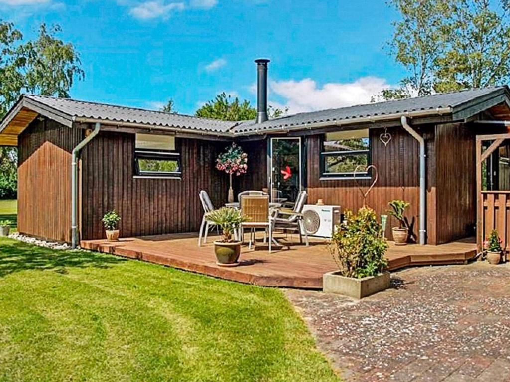 a house with a deck with a table and chairs at 4 person holiday home in Slagelse in Slagelse