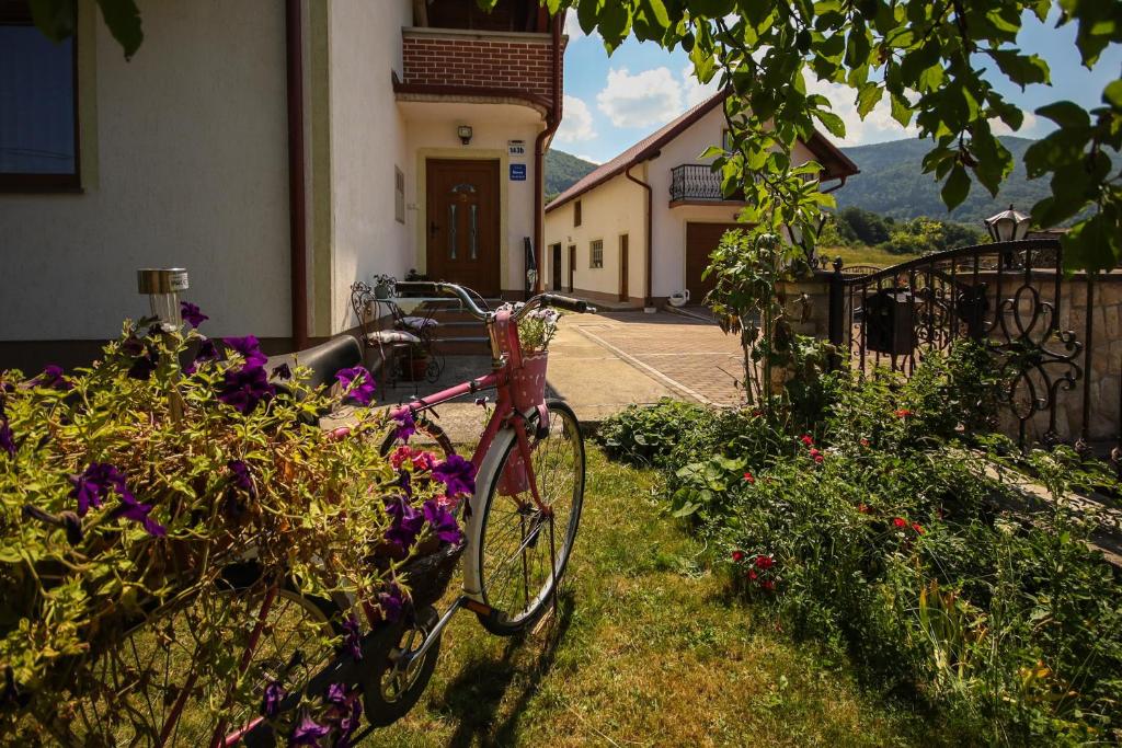 a pink bike parked in a garden with flowers at Apartman Lucija & Luka in Otočac