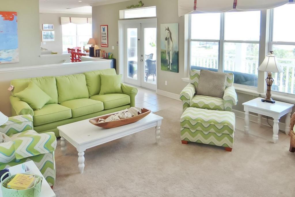 a living room with green couches and a coffee table at Serenity Now in St. George Island
