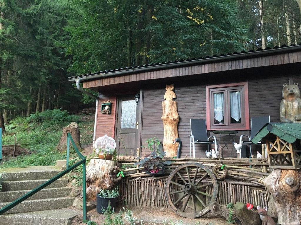 a small house with a wooden cart in front of it at Waldnest Odenwald - Waldhauszimmer in Wald-Michelbach
