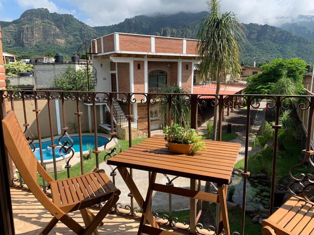 een tafel en een stoel op een balkon met een zwembad bij La Buena Suerte in Tepoztlán