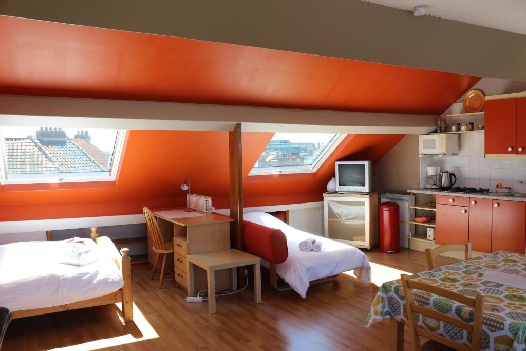 Habitación con 2 camas y cocina con paredes de color naranja. en Brussels BnB, en Bruselas